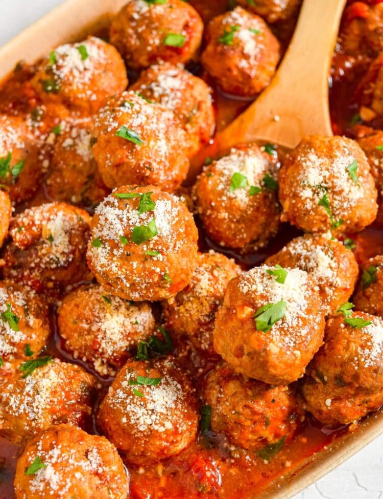Close up image of instant pot meatballs in a serving dish with a wooden spoon.