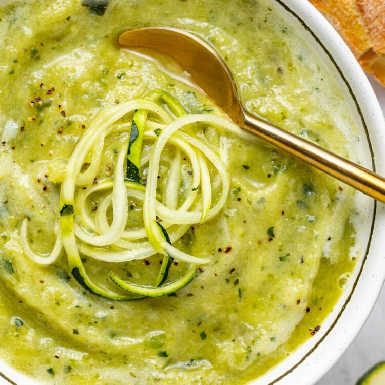 close up image of creamy zucchini soup with spiralized zucchini on top