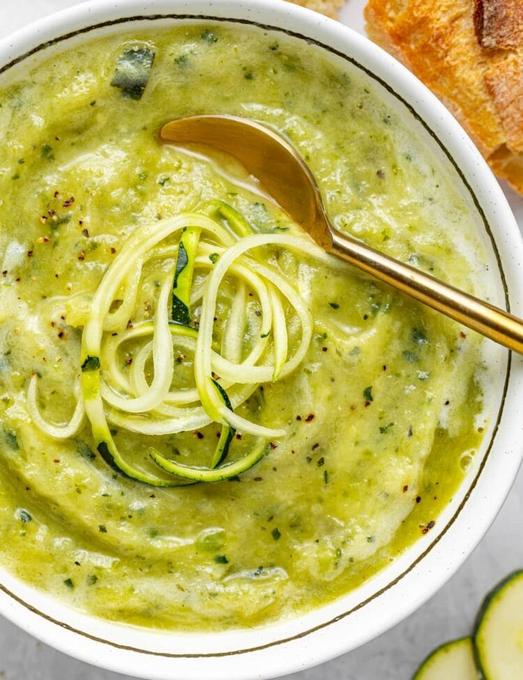close up image of creamy zucchini soup with spiralized zucchini on top