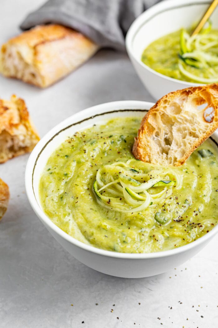 creamy zucchini soup in a bowl with a side of toasted bread