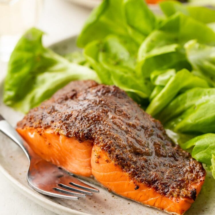 Air fryer salmon on a plate next to a small green salad