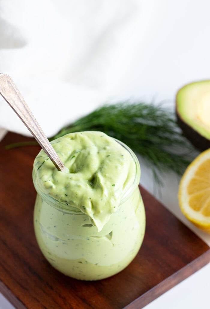 Overhead angle of avocado ranch dressing in a glass jar on a wooden board