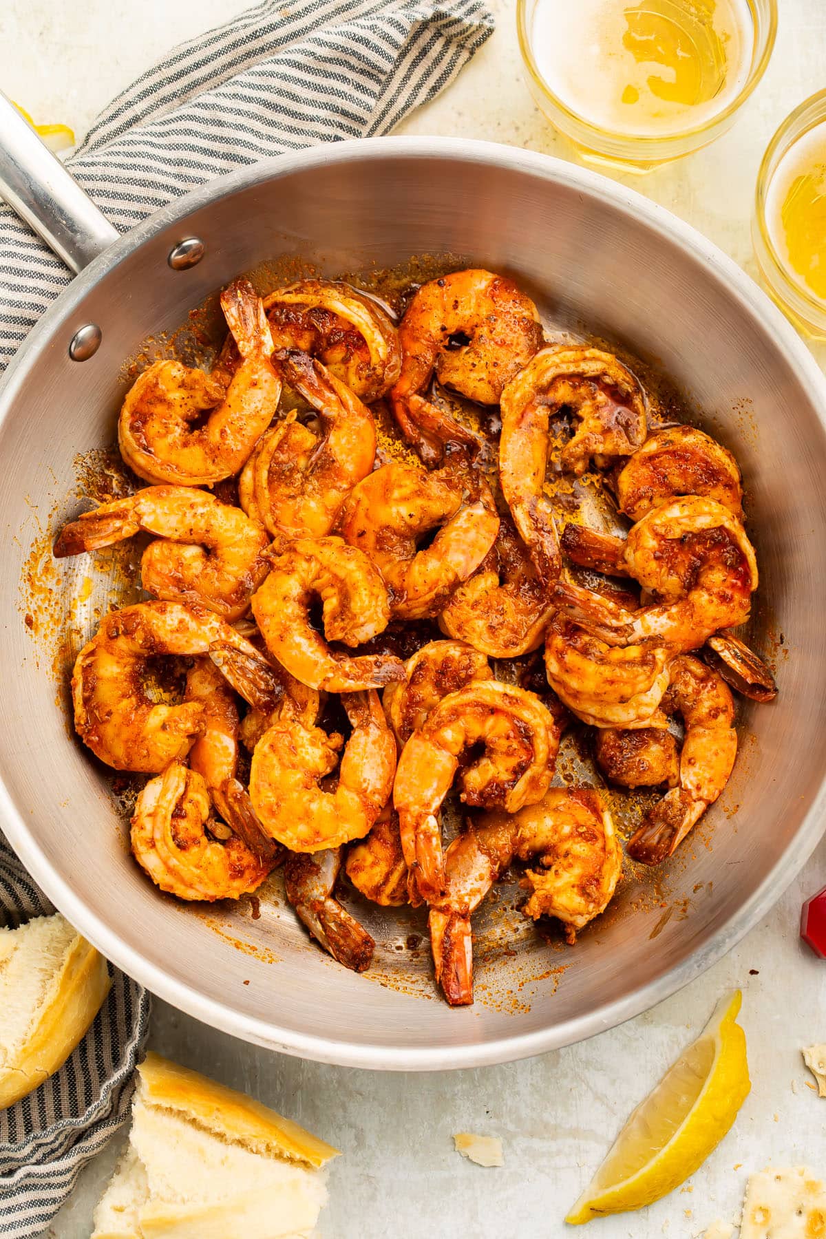 Overhead photo of a large silver skillet full of a tender, slightly curled Cajun shrimp.