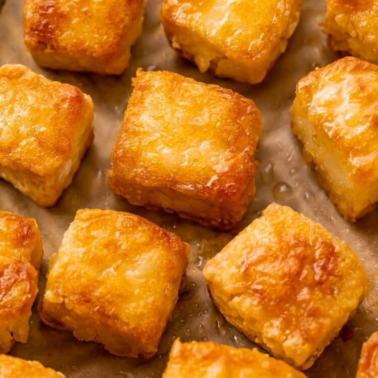 Close up photo of crispy baked tofu squares on a baking sheet