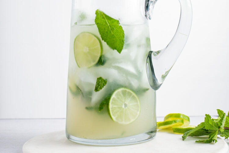 Chilled mint mojitos in a pitcher with lime coins and fresh mint leaves.
