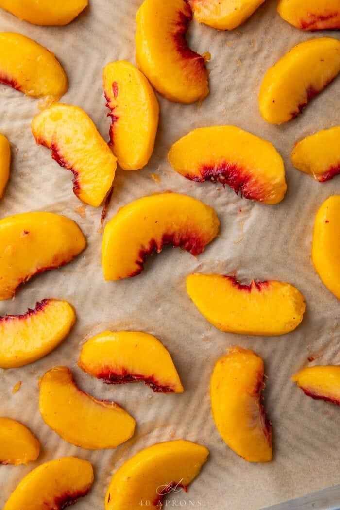Peach wedges on a baking sheet lined with parchment paper