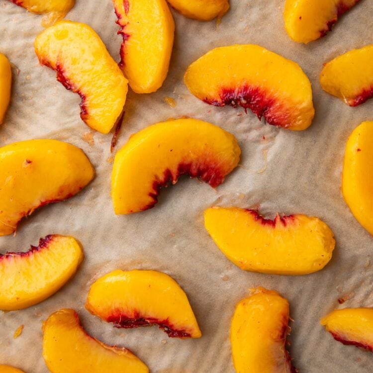 Peach wedges on a baking sheet lined with parchment paper