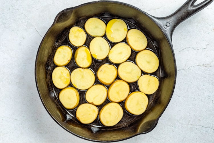 Raw potato slices in a large cast-iron skillet.
