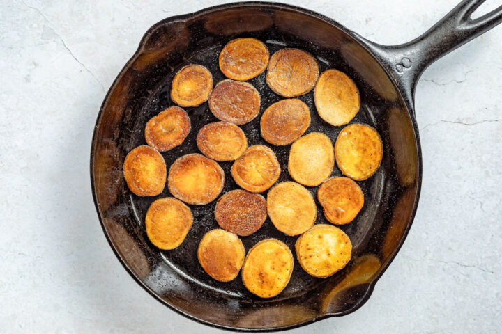 Browned baby potatoes in a large cast-iron skillet.