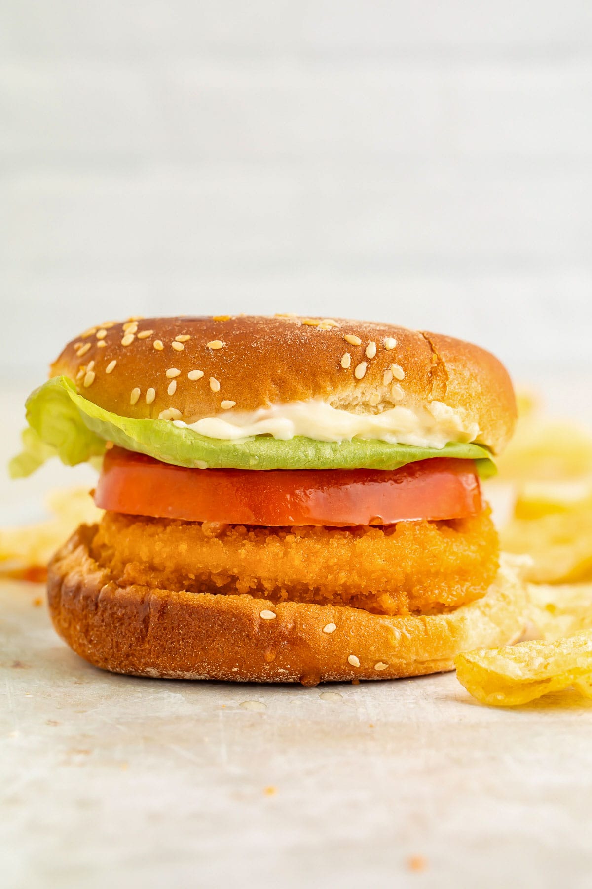 Air fryer frozen chicken patty sandwiched between two bun halves with a thick slice of tomato and iceberg lettuce.