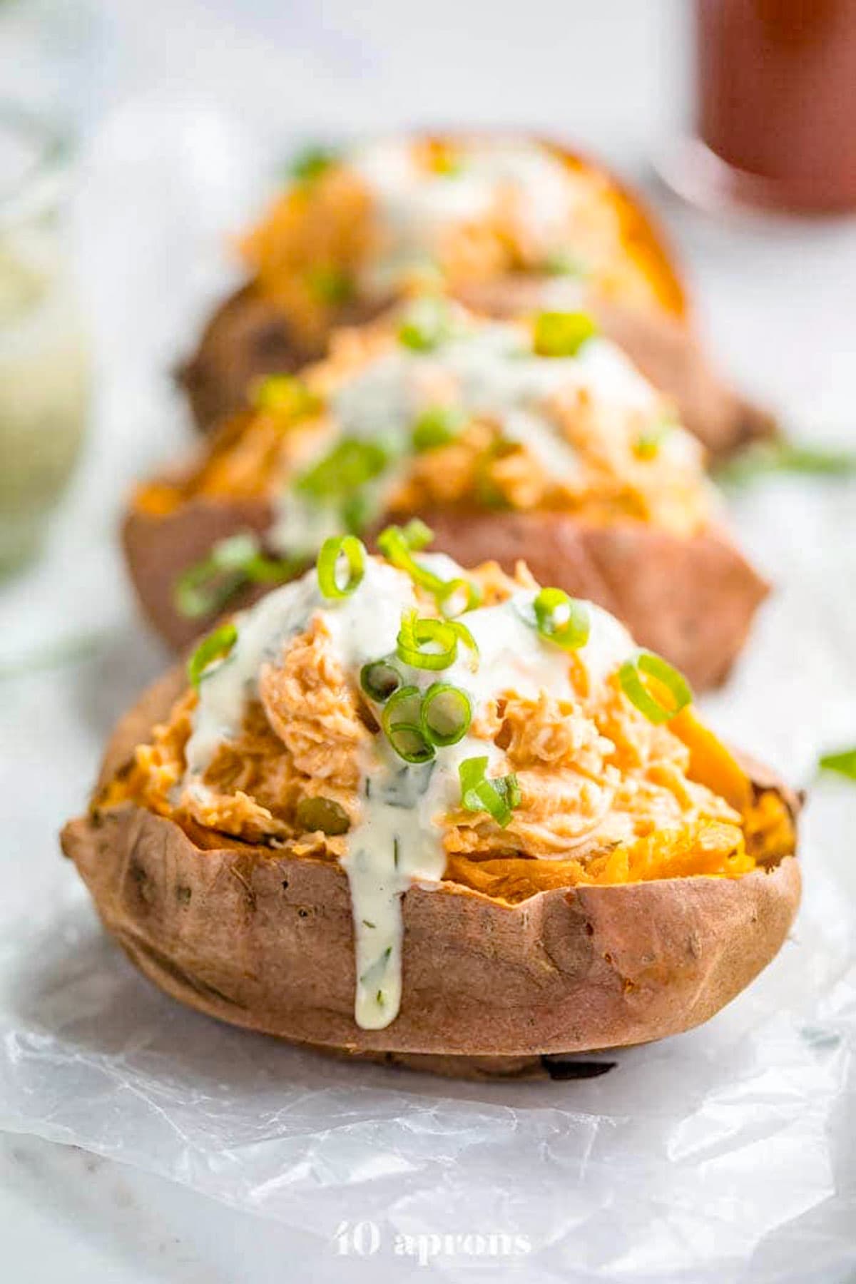 Sweet potatoes stuffed with shredded buffalo chicken topped with a creamy dressing and fresh herbs.