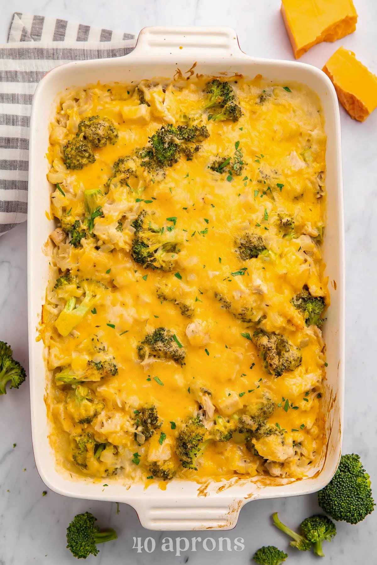 A large rectangular white casserole dish holding a baked cheesy chicken broccoli rice casserole.