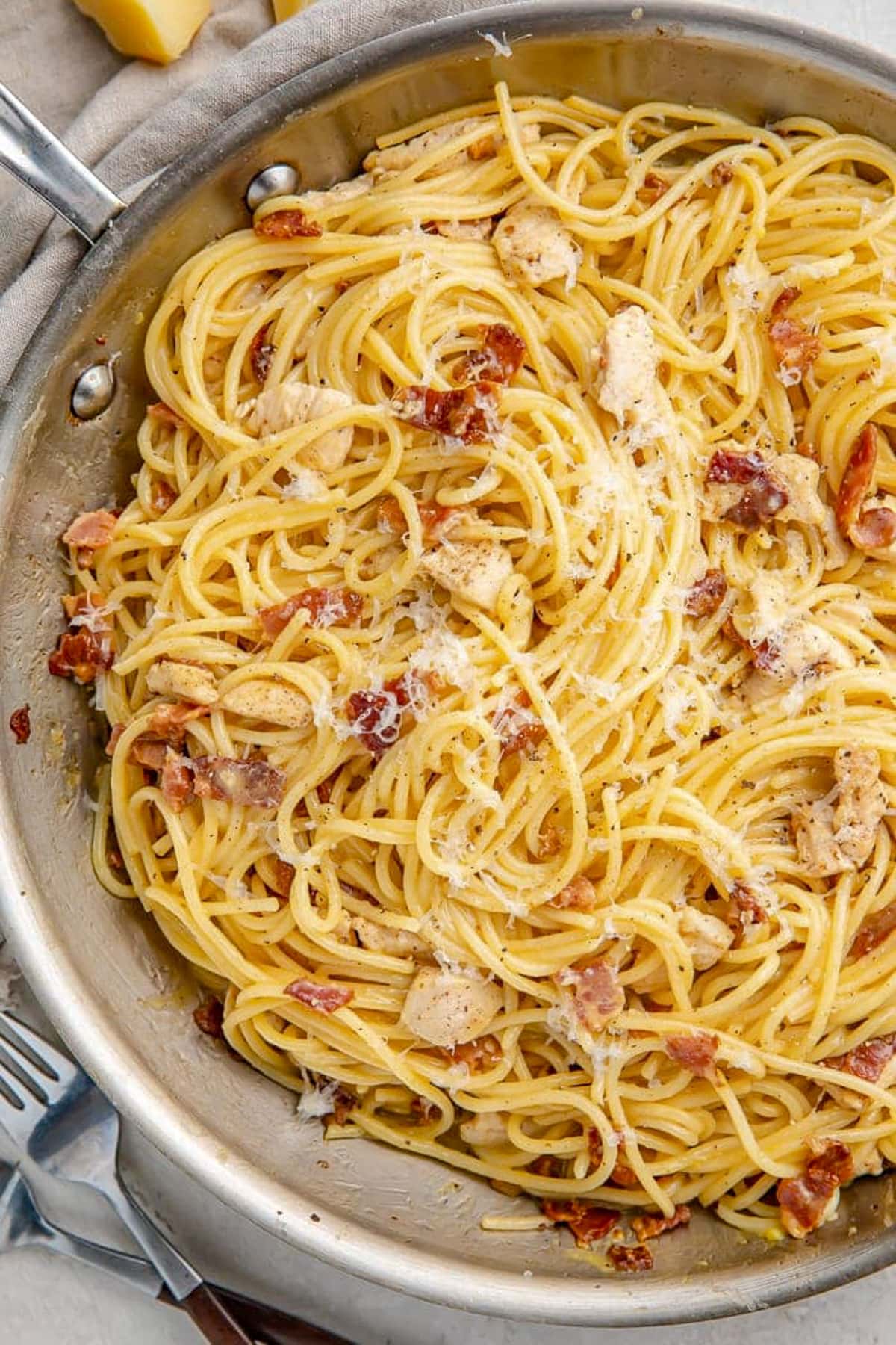 Chicken carbonara with angel hair pasta in a large silver skillet.