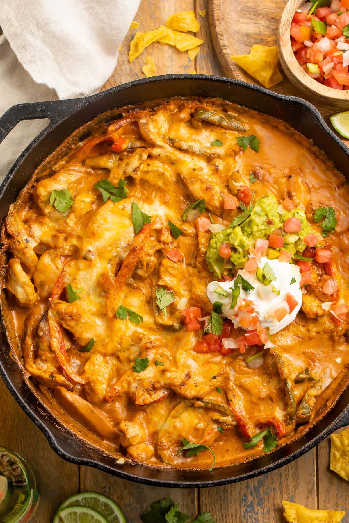 Top-down view of chicken fajita casserole with a creamy sauce in a large black cast iron skillet.