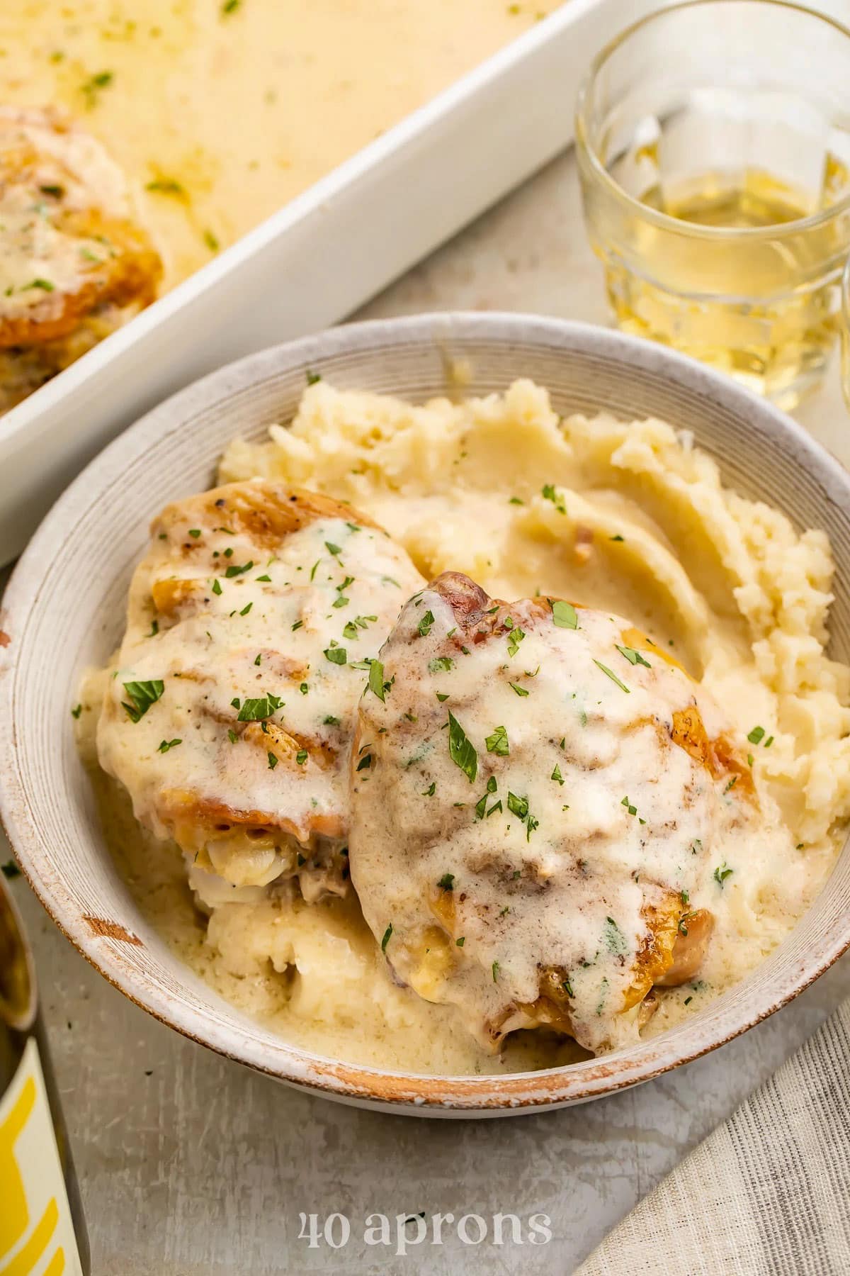 A bowl holding a bed of whipped mashed potatoes topped with chicken and a creamy chicken soup sauce.
