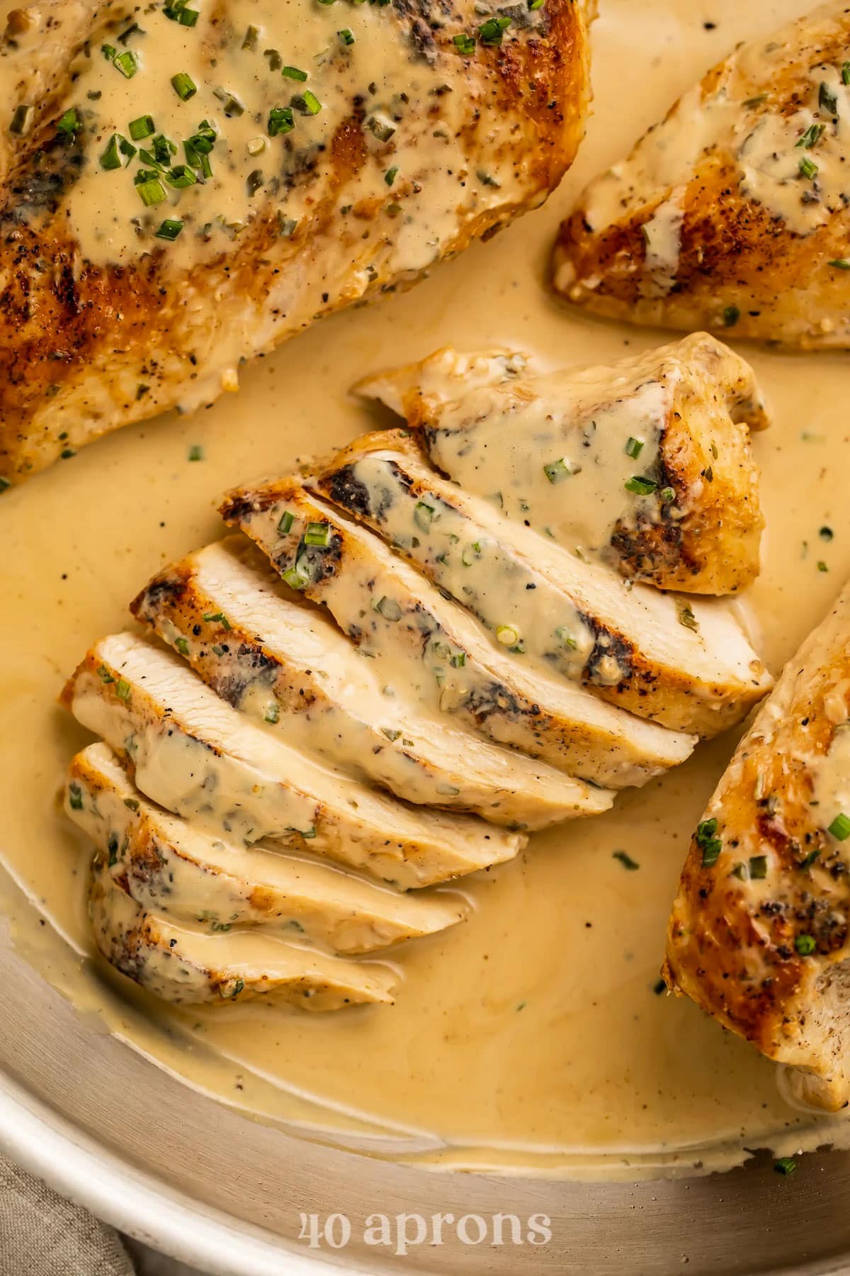 Close-up of a sliced chicken breast sitting in and topped with a creamy Boursin cheese sauce.