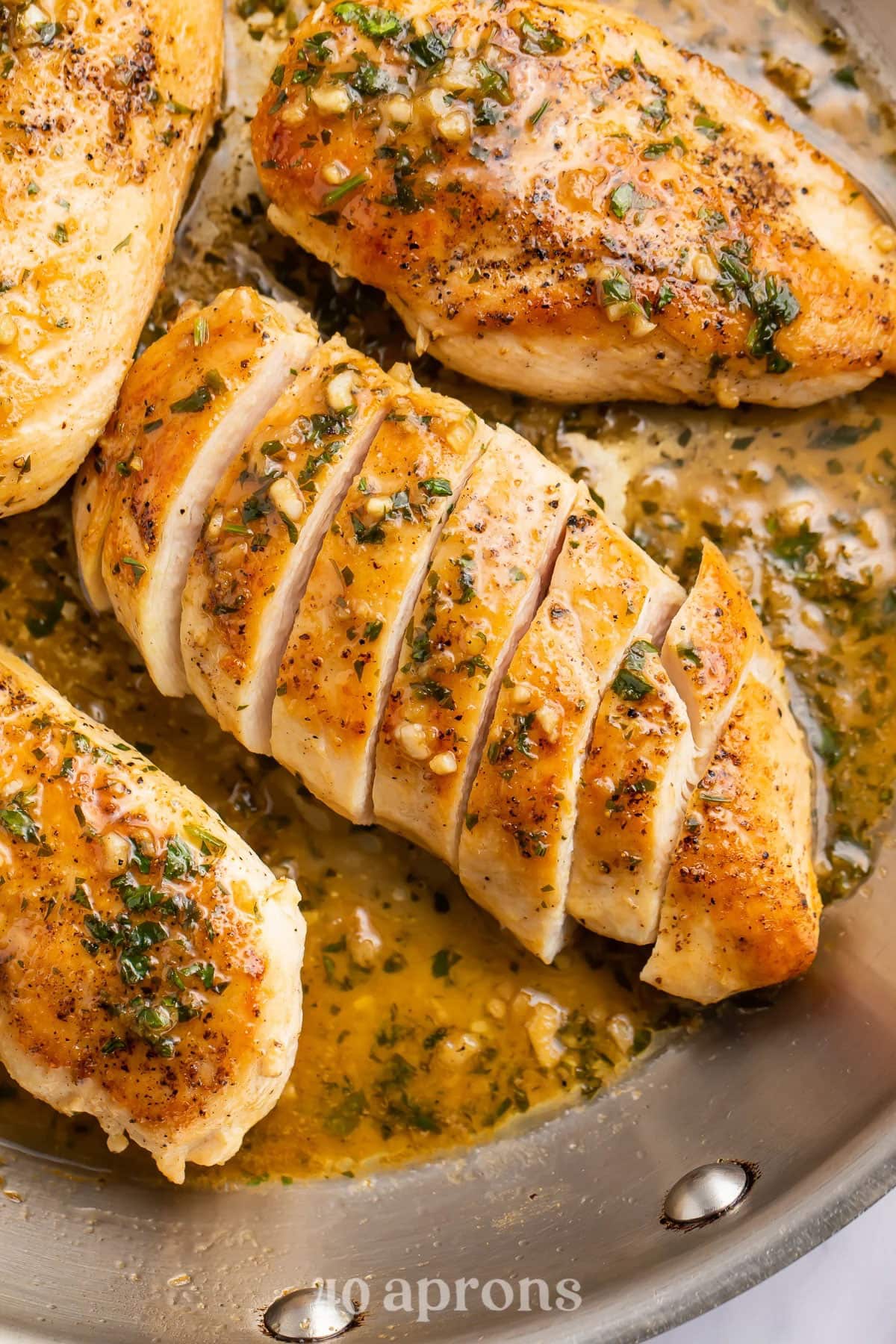 Sliced chicken breast in a large skillet with a garlic butter sauce.