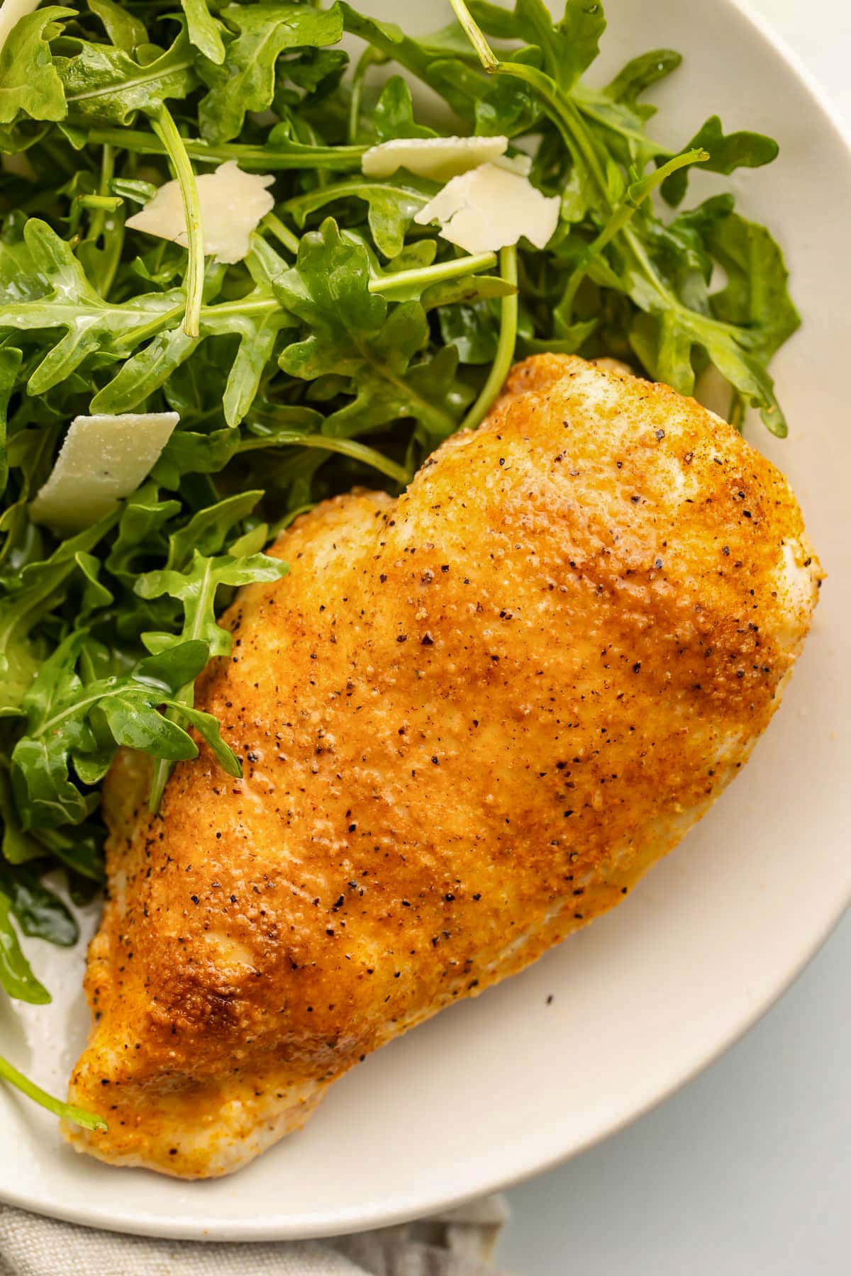 A chicken breast, cooked in the Instant Pot, on a neutral plate with a small side salad.
