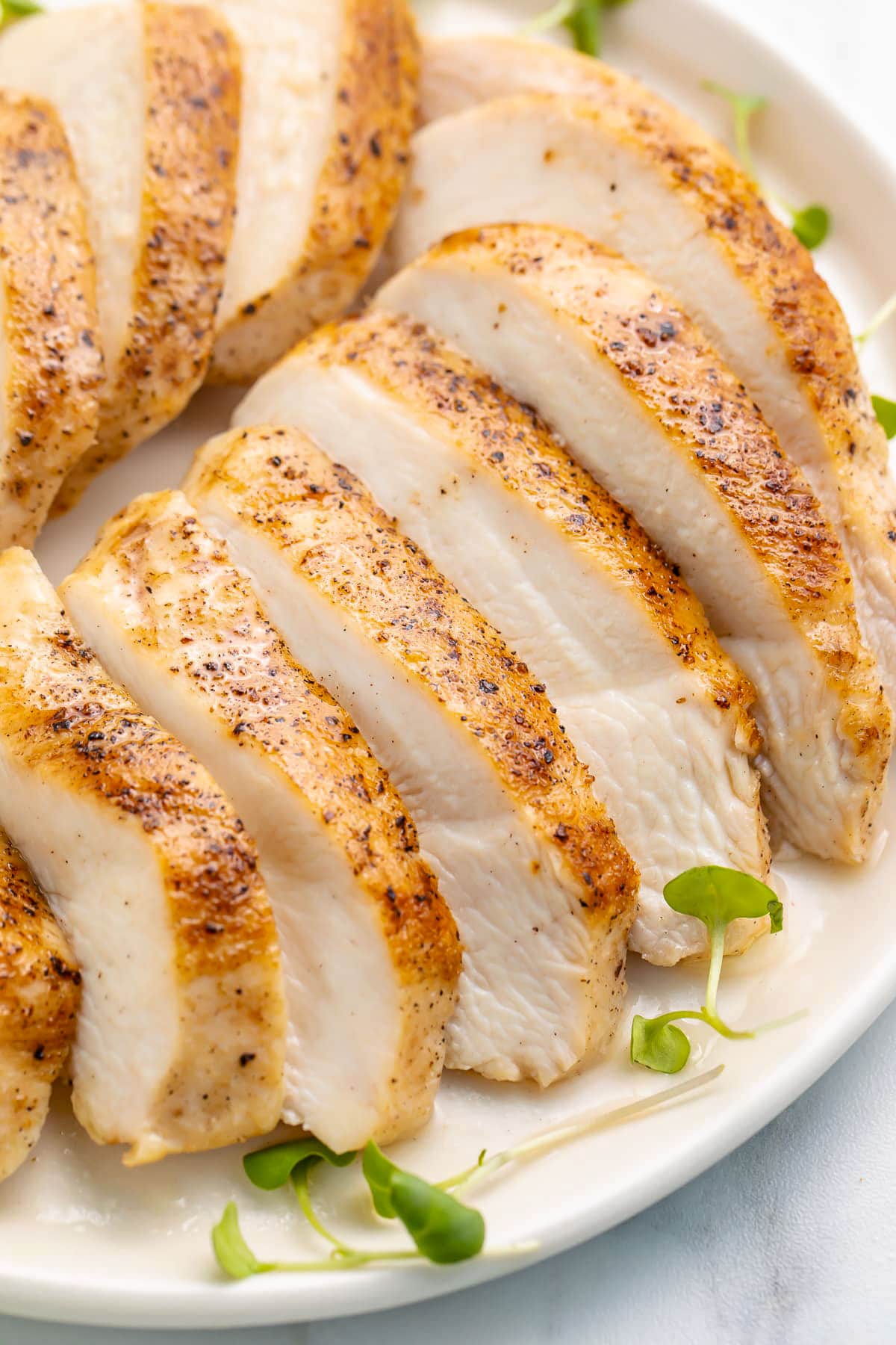 Chicken breasts, cooked until tender in a sous vide water bath, then sliced and plated on a white plate.