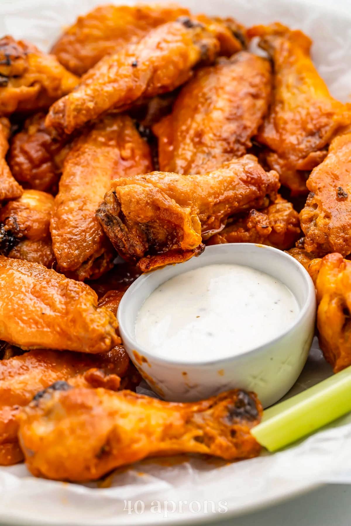 A platter of Whole30 buffalo chicken wings with a small dipping bowl of Whole30 ranch dressing and celery sticks.