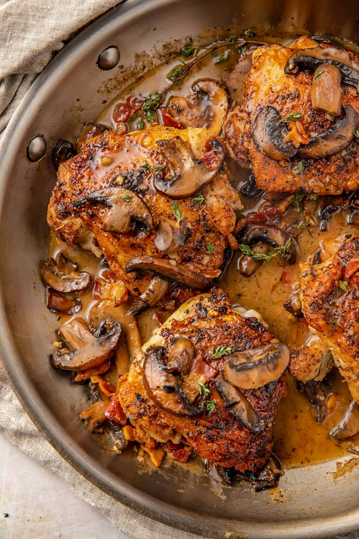 Creamy Whole30 bacon mushroom chicken thighs in a large silver skillet.