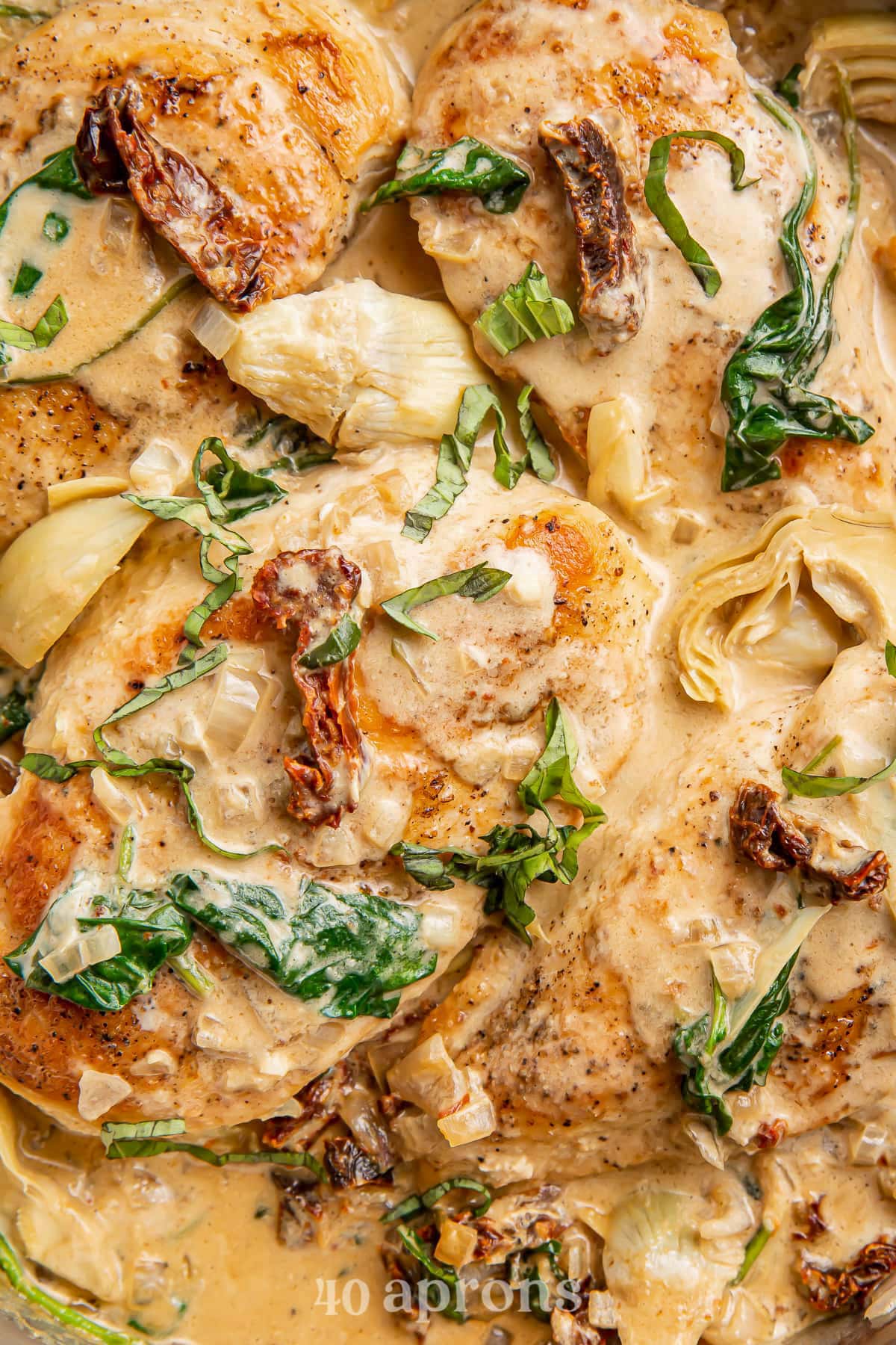 Close-up of Whole30 creamy tuscan chicken in a skillet with spinach.