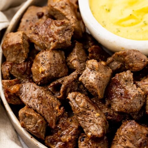 A platter of garlic steak bites with a bowl of microwave bearnaise sauce