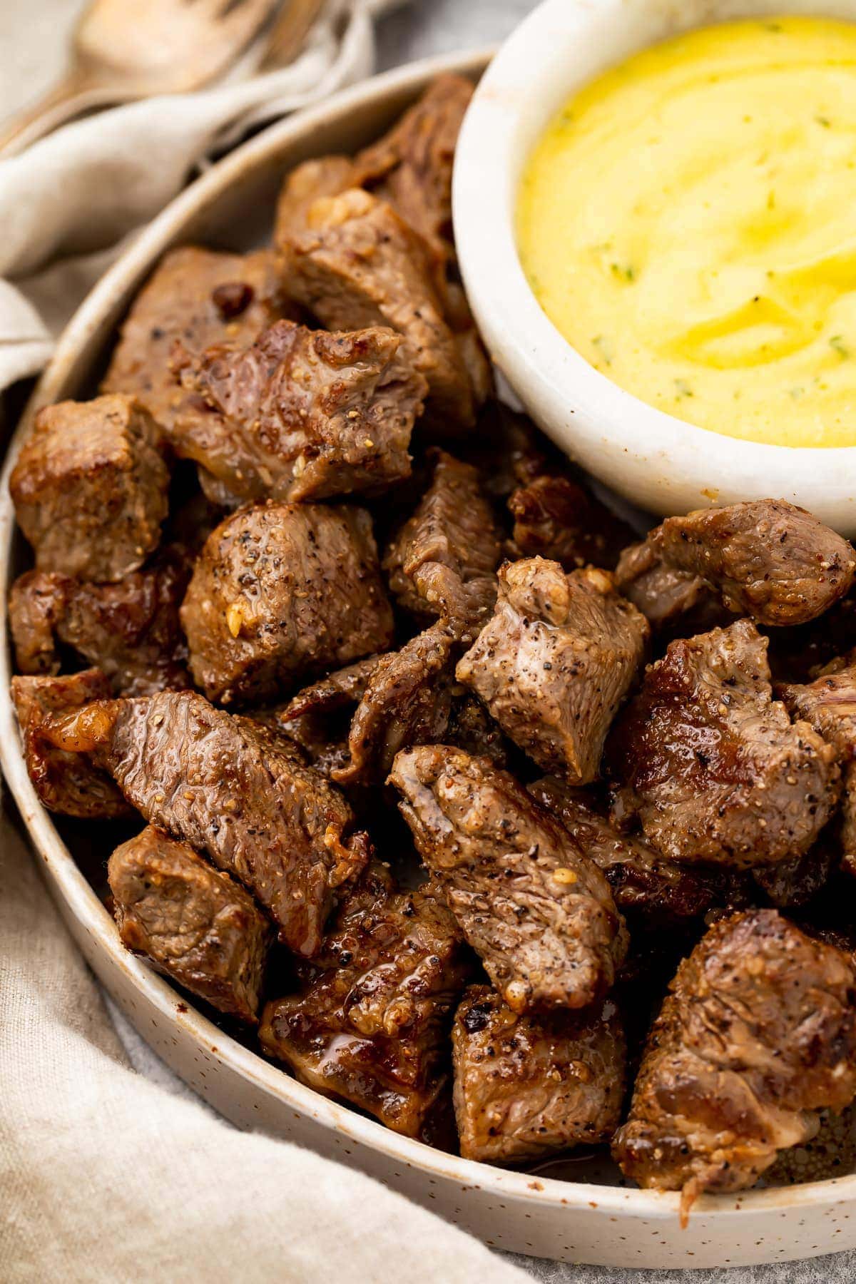 A platter of garlic steak bites with a bowl of microwave bearnaise sauce