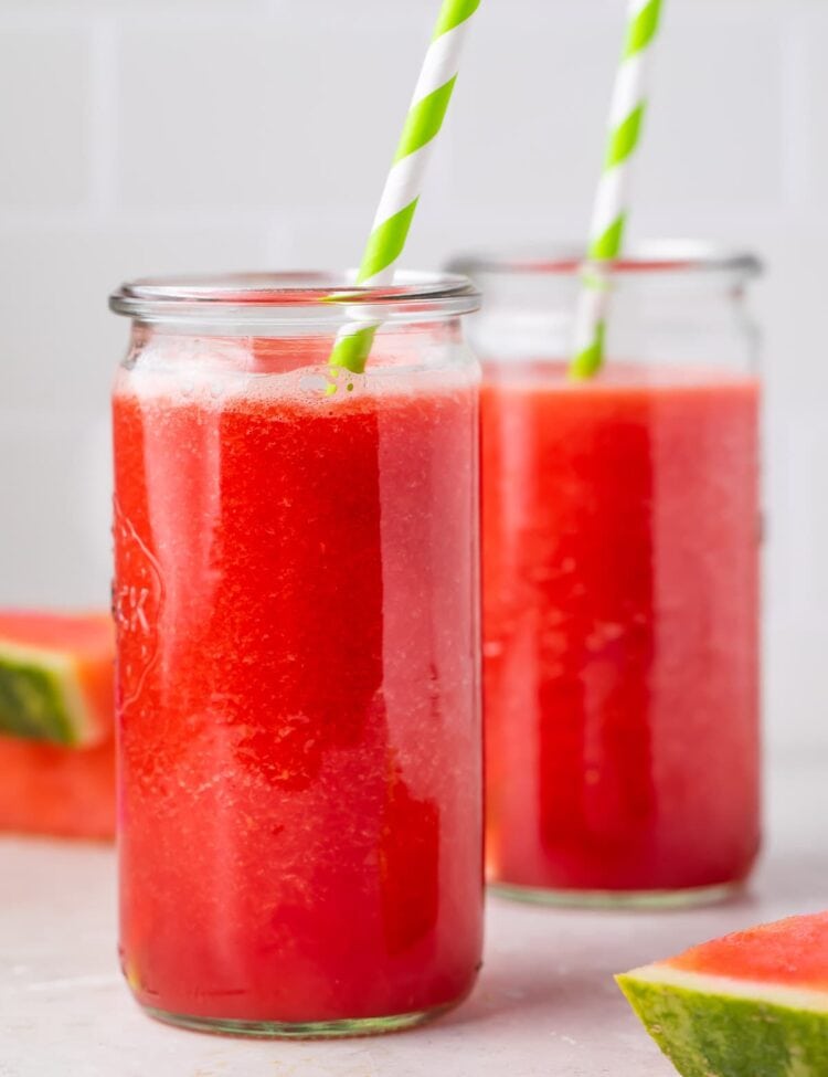 Two glasses of watermelon juice with green and white striped straws