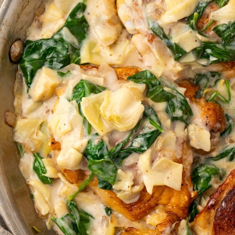 Close up photo of paleo spinach and artichoke chicken in a large silver pan