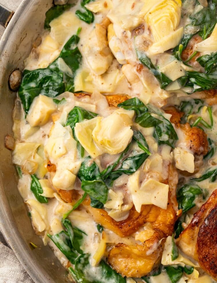 Close up photo of paleo spinach and artichoke chicken in a large silver pan