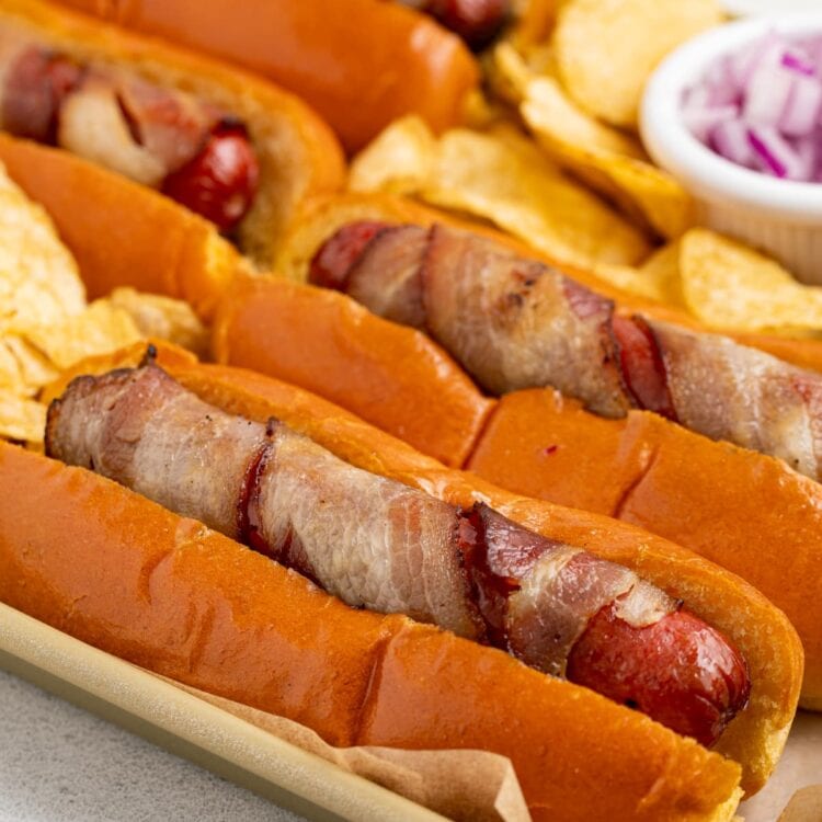 close up image of bacon wrapped hot dogs on a tray