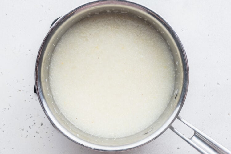 Overhead view of grits and water in large silver saucepan.