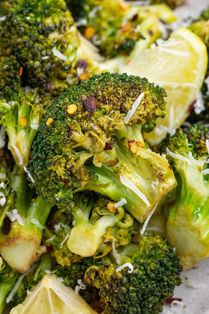 close up image of grilled broccoli on a plate with lemon slices