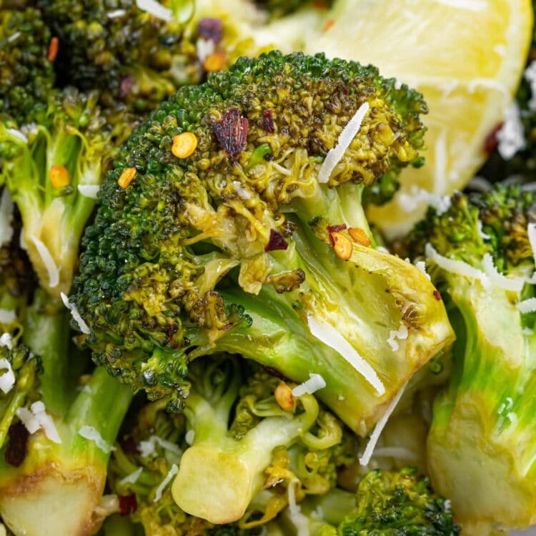 close up image of grilled broccoli on a plate with lemon slices