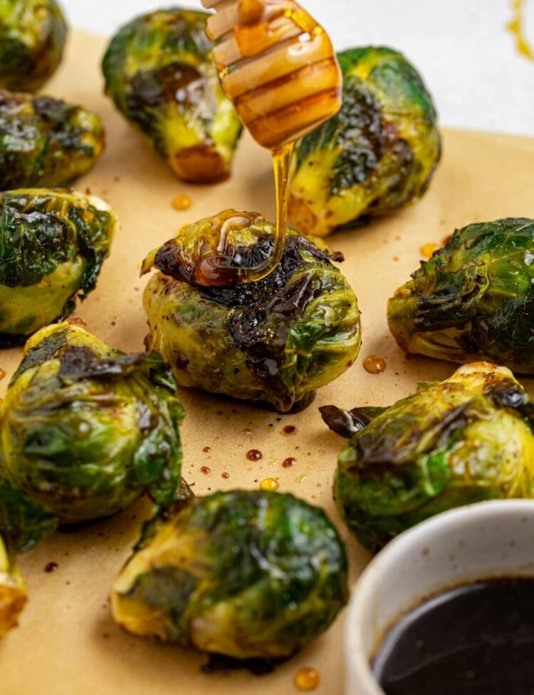 grilled brussels sprouts with honey being dripped over the top