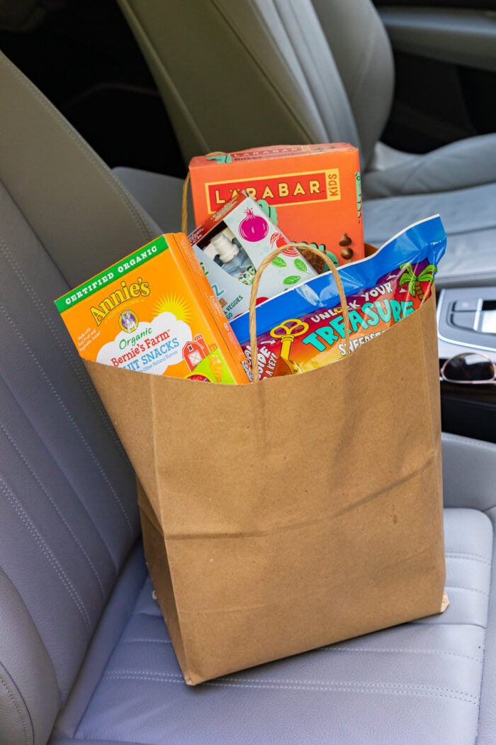 Bag of road trip snacks in a car seat