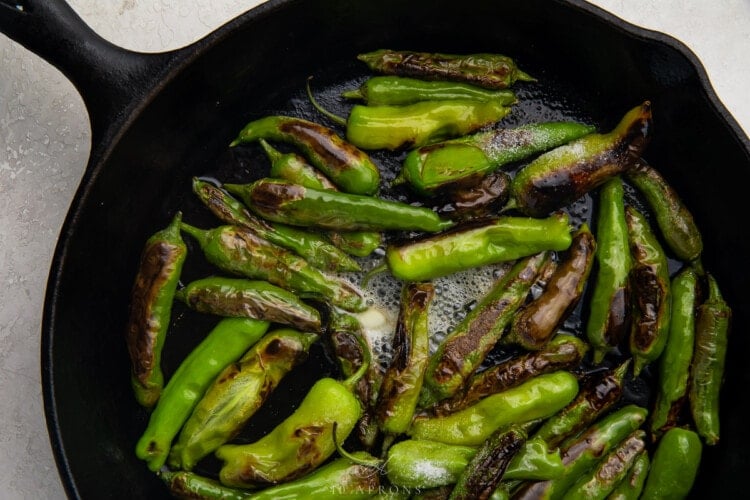 Shishito peppers in butter in a large cast iron skillet