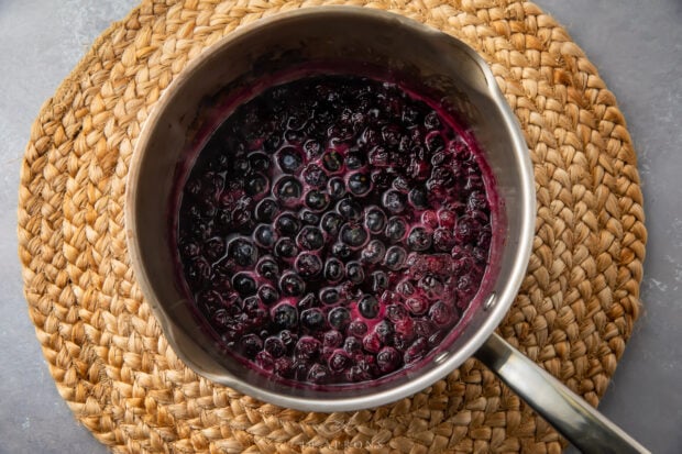 Blueberry compote in heavy saucepan with wicker placemat in background