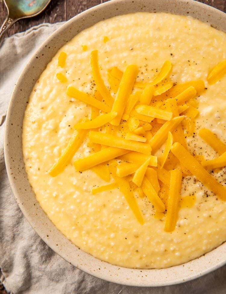Cheese grits in a tan bowl with shredded cheese on top
