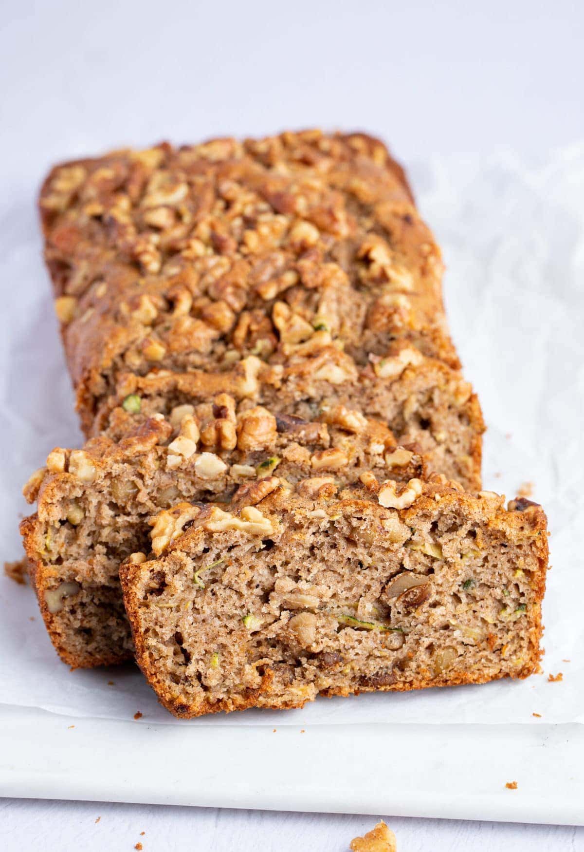 Slices of gluten free zucchini bread angled against each other on a white surface