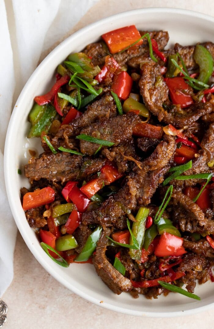 Hunan beef in a large white bowl on a white table