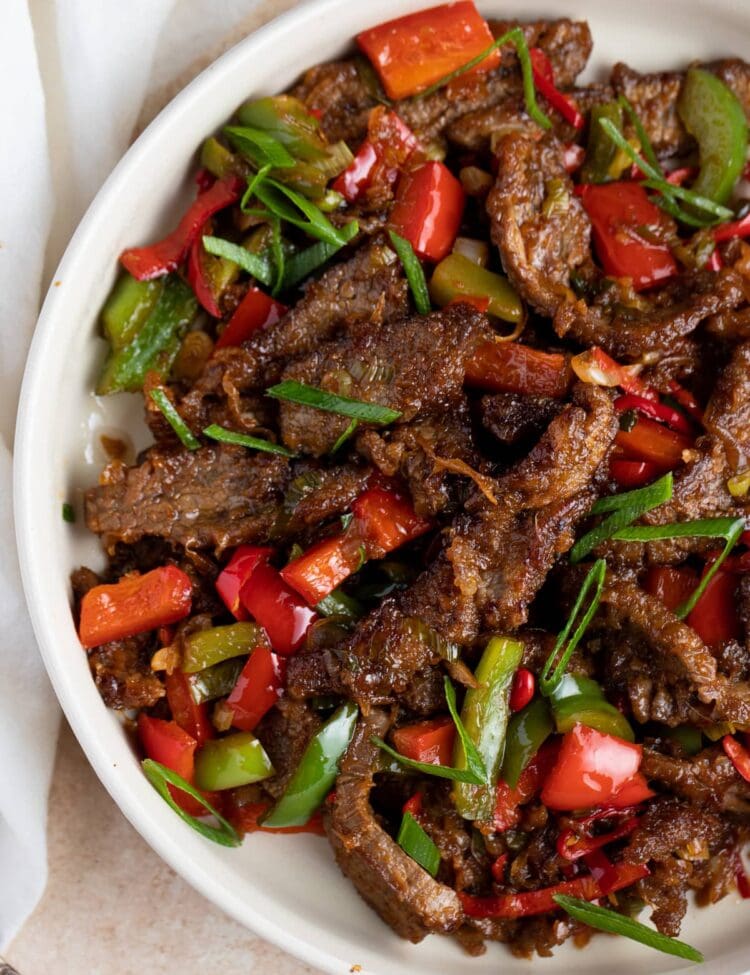 Hunan beef in a large white bowl on a white table