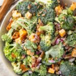 Keto broccoli salad in a large bowl next to a wooden spoon