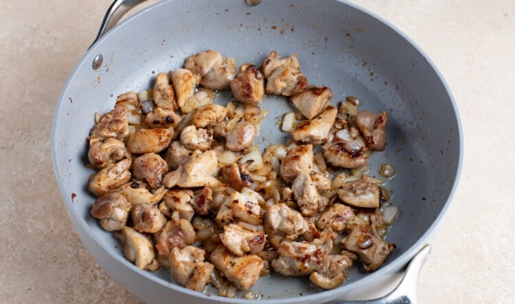 Browned chicken pieces with onion in a large skillet