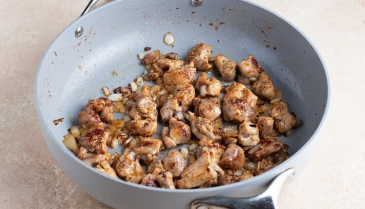Browned chicken with onion, ginger, and garlic in large skillet