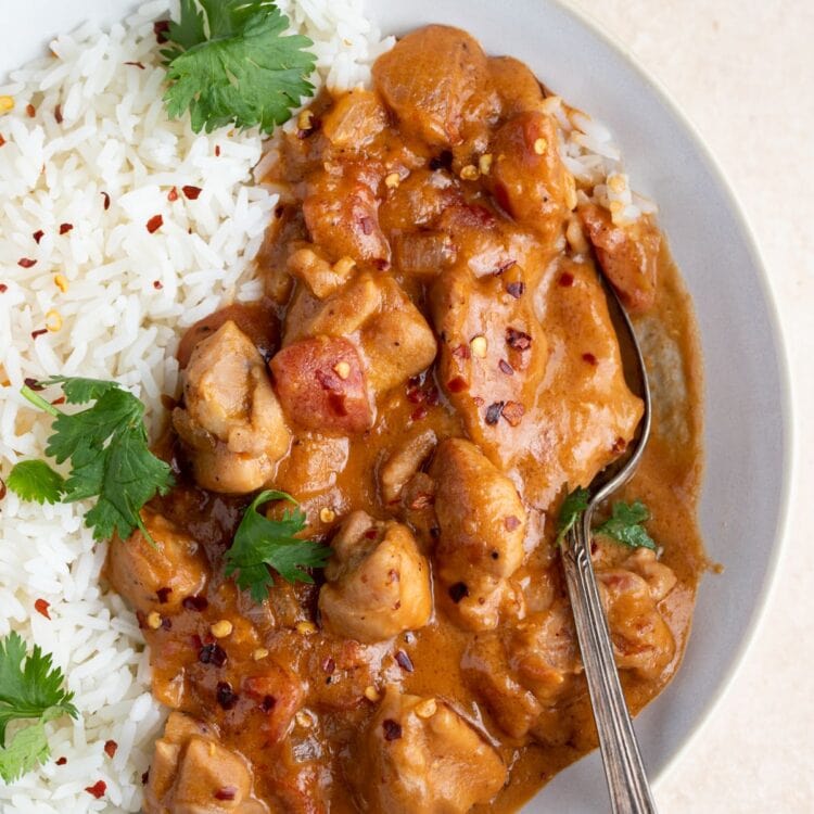 Overhead angle of peanut butter chicken and rice in a white bowl with a spoon