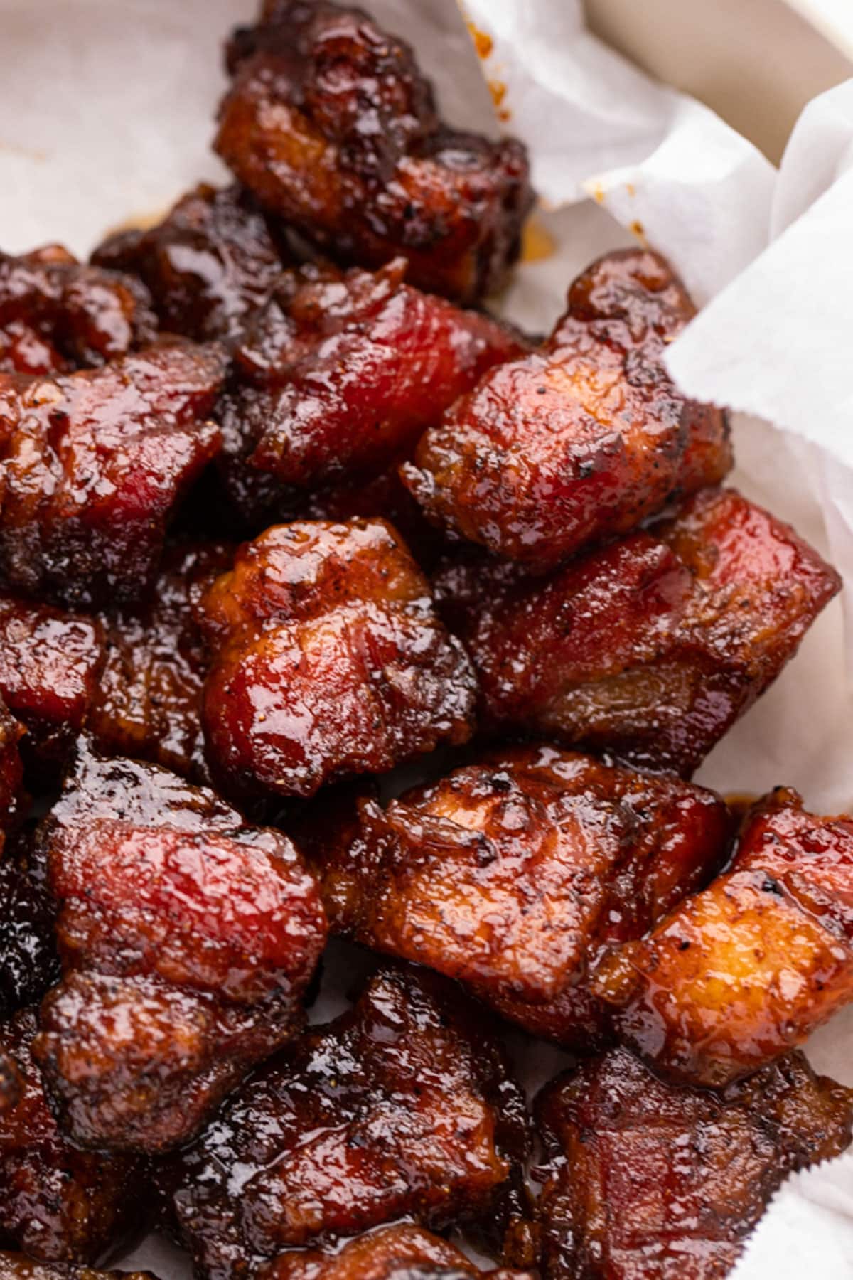 Pork belly burnt ends on white parchment paper.