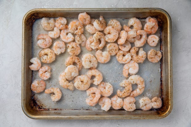 Uncooked shrimp seasoned and spread out on sheet pan