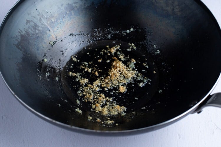 Large wok with oil, ginger, and garlic
